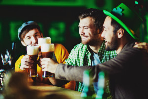Happy guys with glasses of foaming beer spending time in pub
